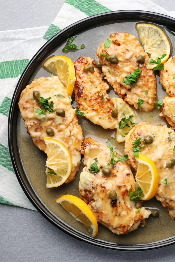 Giada De Laurentiis Chicken Piccata arranged on a plate with lemon slices and capers.