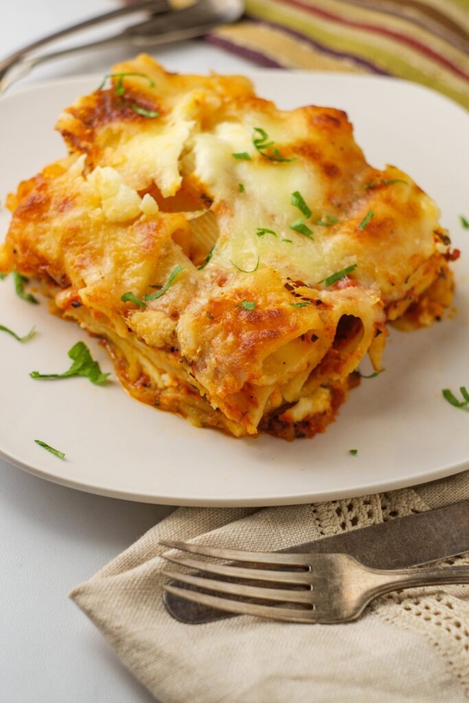 A serving of Giada De Laurentiis Baked Lemon Ziti on a white plate with parsley garnish.