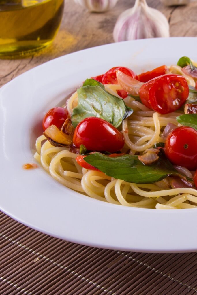 Giada De Laurentiis Cherry Tomato Spaghetti with basil on a white plate.