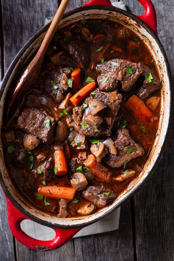 Giada De Laurentiis beef bourguignon with carrots and mushrooms in a red Dutch oven.