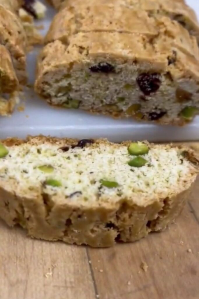 Cherry-pistachio biscotti drizzled with chocolate on parchment paper.