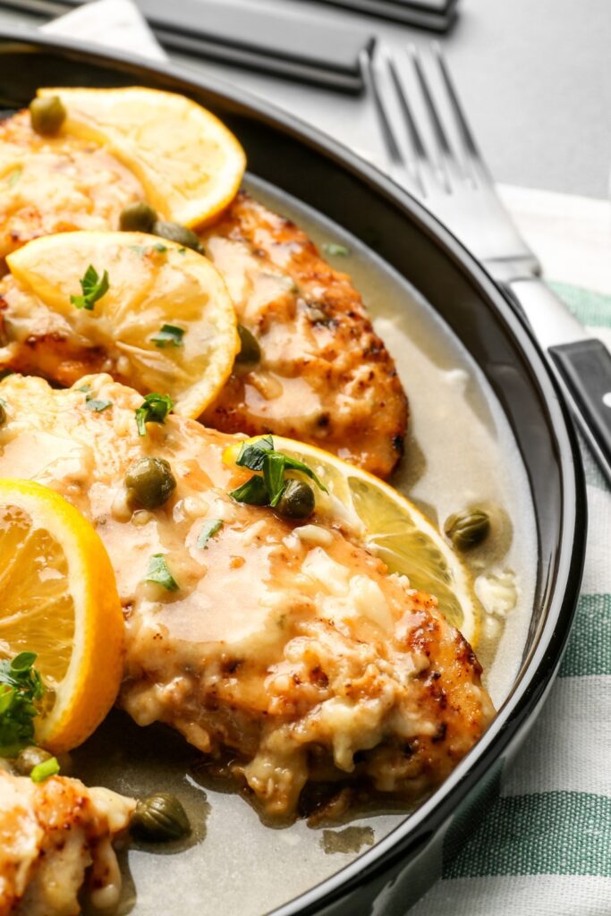 Giada De Laurentiis Chicken Piccata with lemon slices and capers on a plate.