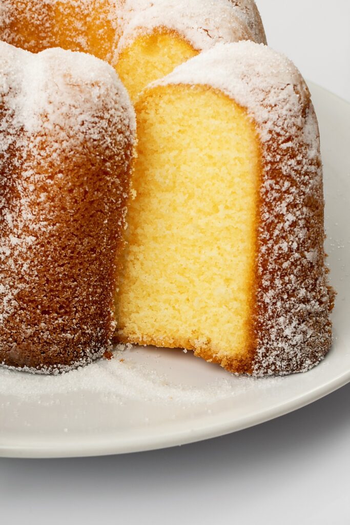 Giada De Laurentiis Ciambella cake with a slice cut out, dusted with powdered sugar.