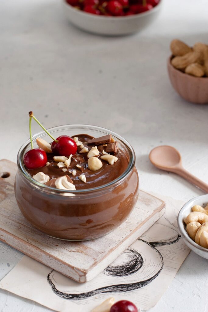 Chocolate rice pudding topped with cherries and nuts in a glass bowl.