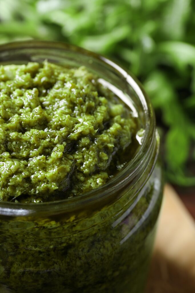 Bowl of Giada De Laurentiis Arugula Pesto with olive oil being poured in.