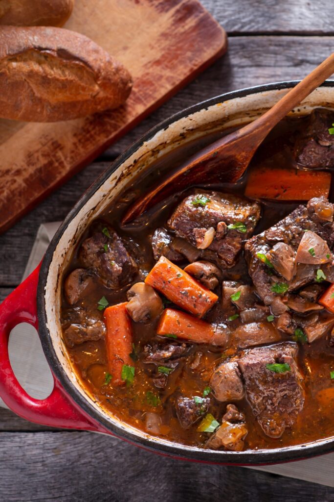 Giada De Laurentiis beef bourguignon in a red Dutch oven with bread on the side.