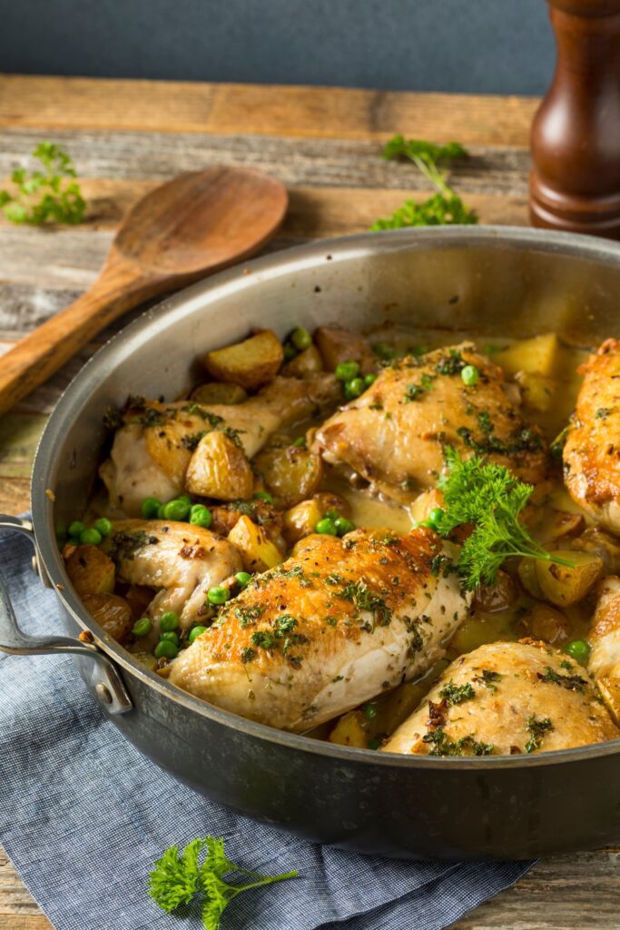 Giada De Laurentiis Chicken Vesuvio in a skillet with potatoes, peas, and herbs.