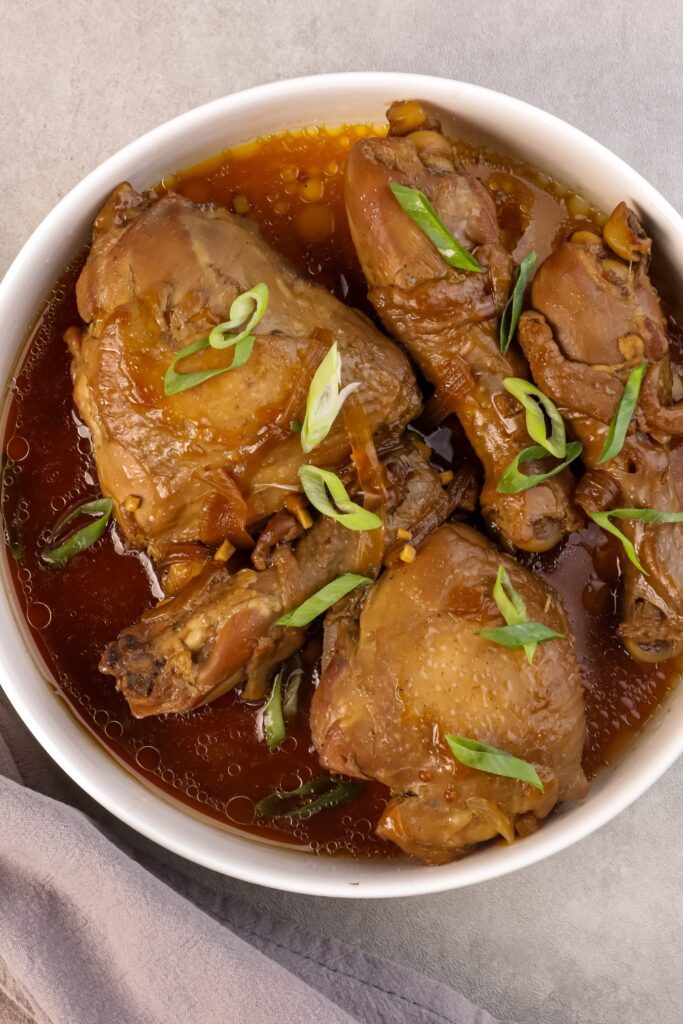 Bowl of Chicken Adobo with green onions on top.