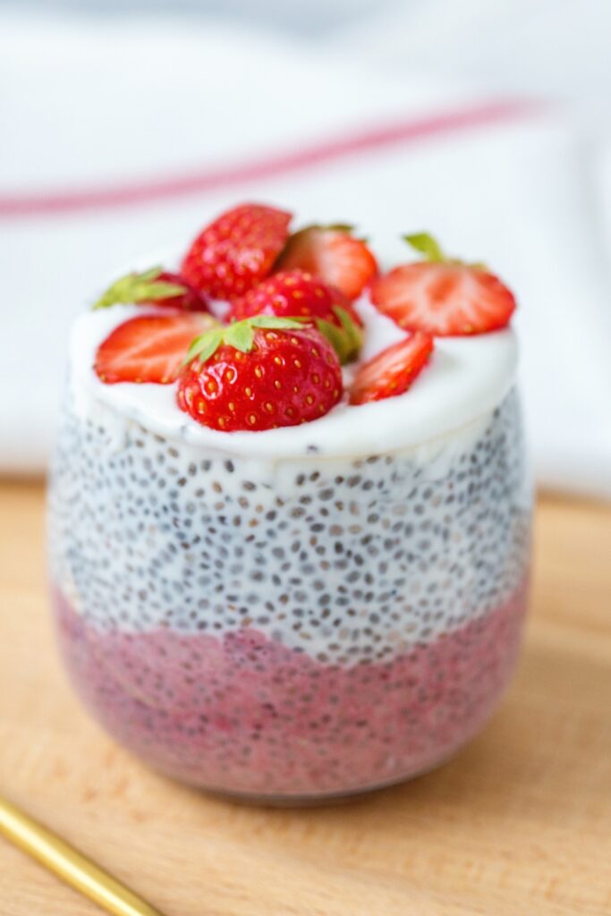 Chia seed pudding topped with fresh strawberries in a clear glass.