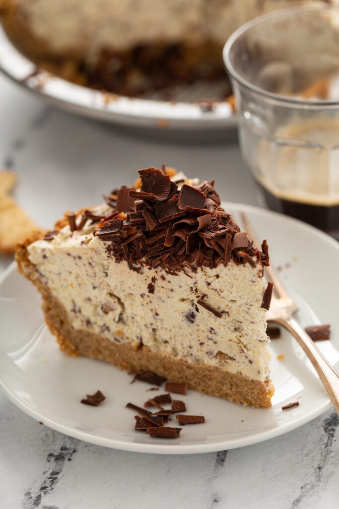 Whole chocolate ricotta cheesecake with chocolate shavings on a marble surface.