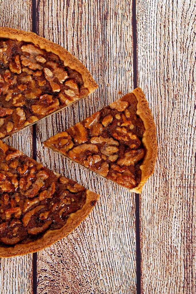 Sliced brownie walnut pie on a wooden table.