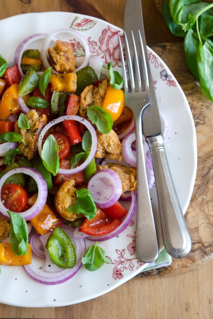 panzanella salad with tomatoes, bell peppers, red onions, basil, and croutons.