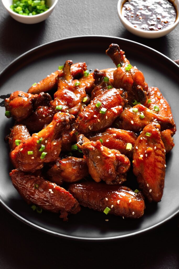 Sticky baked chicken wings garnished with green onions and sesame seeds.