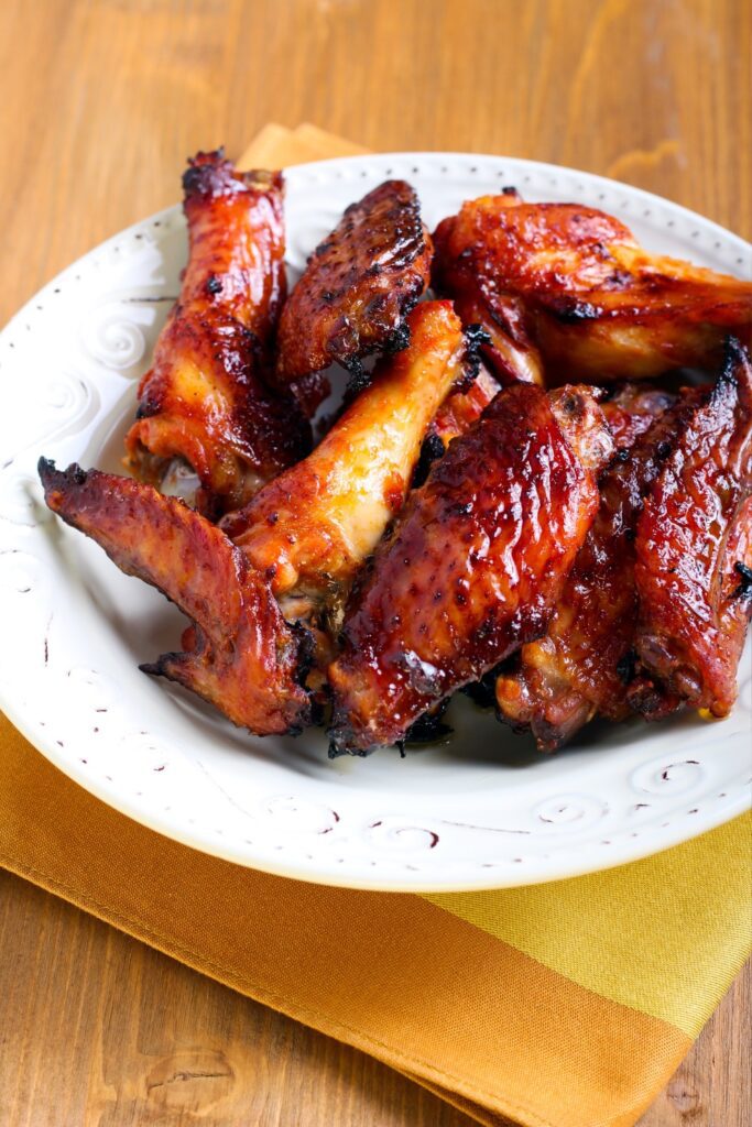 Sticky baked chicken wings on a white plate.