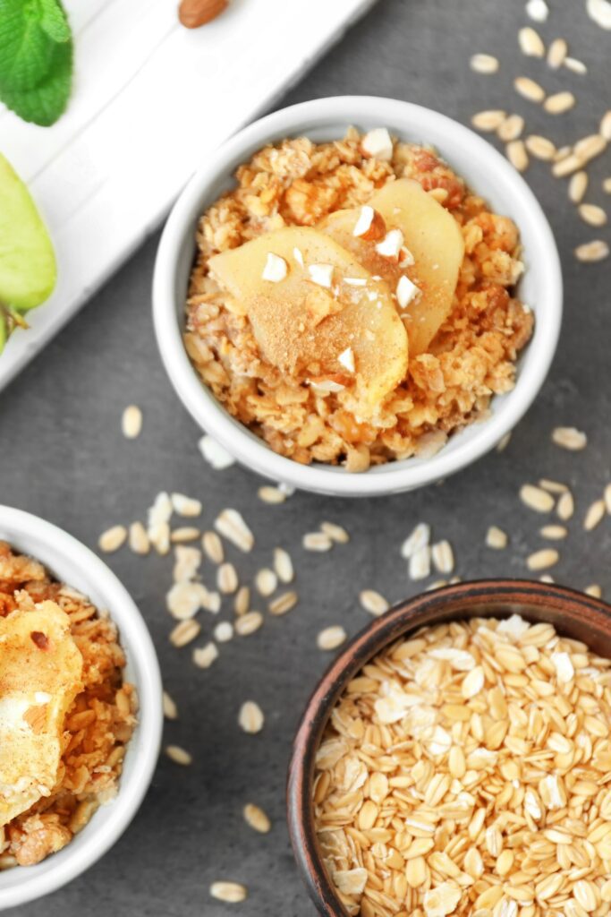 Bowls of vegan apple crisp with sliced apples and oats.