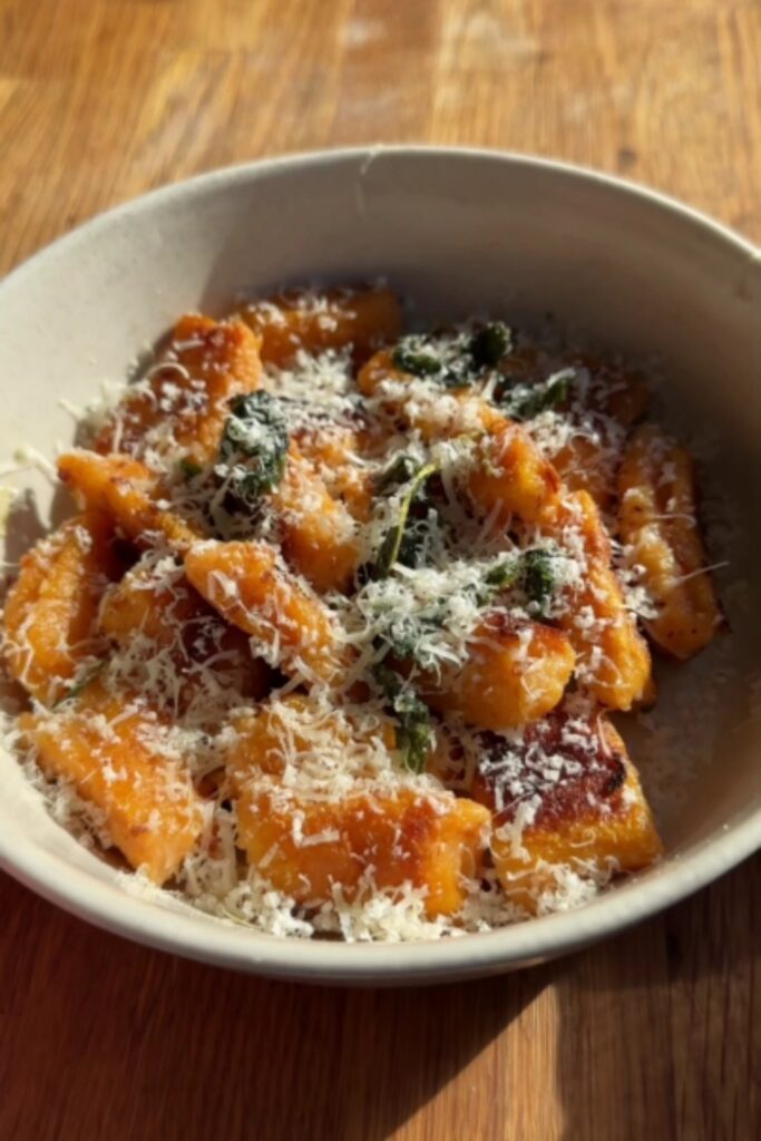 Giada Sweet Potato Gnocchi in a bowl with a generous sprinkle of Parmesan, served in a light bowl.