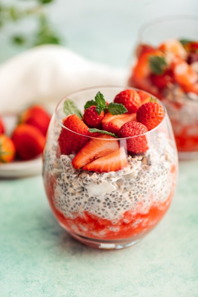 Chia seed pudding layered with fresh strawberries and topped with mint in a glass.