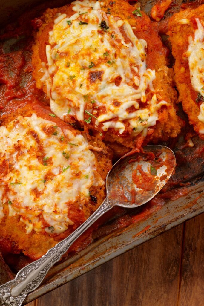 chicken Parmesan topped with melted cheese and fresh parsley in a skillet.