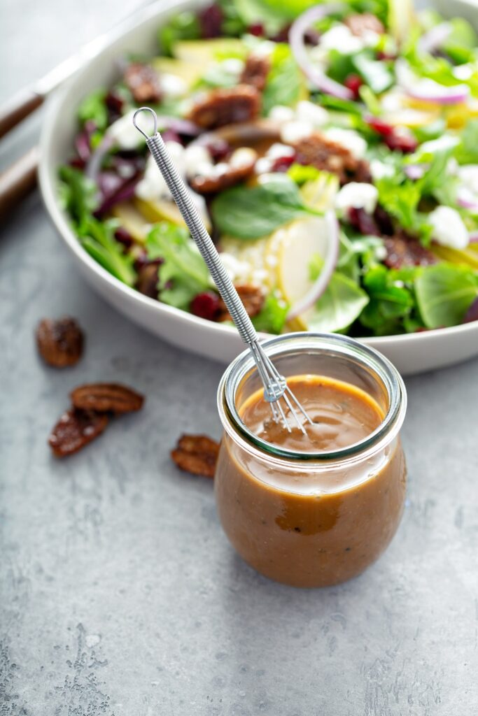 Balsamic vinaigrette in a jar with salad ingredients in the background.